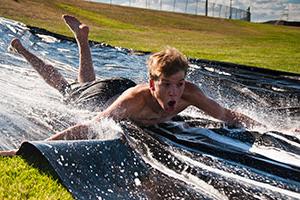 A male student uses the slip and slide at Green and Gold Days.
